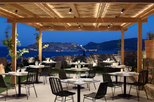 The Kelari Gourmet Restaurant at the Cayo Exclusive Resort & Spa in Crete, Greece, featuring a scenic, outdoor terrace overlooking Spinalonga island.