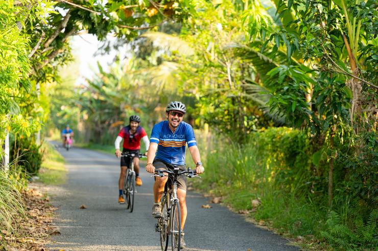 Two Backroads guests cycle on a lush pathway in Vietnam.