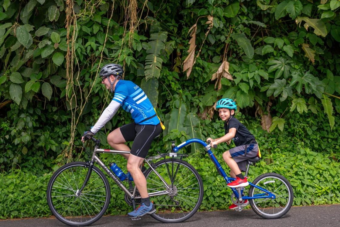 Father and son on a Backroads Family Trip, riding a bike with trailer cycle attached.