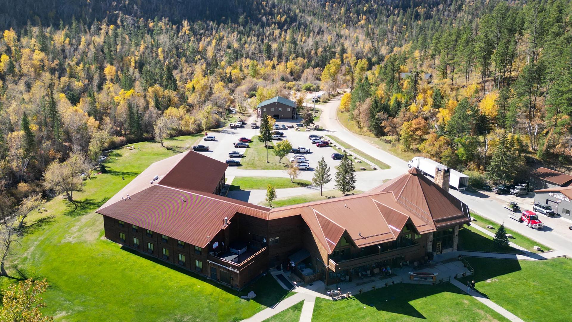 Arial view of the  Spearfish Canyon lodge in Lead. A green pavilion and a mountainous horizon can be seen.