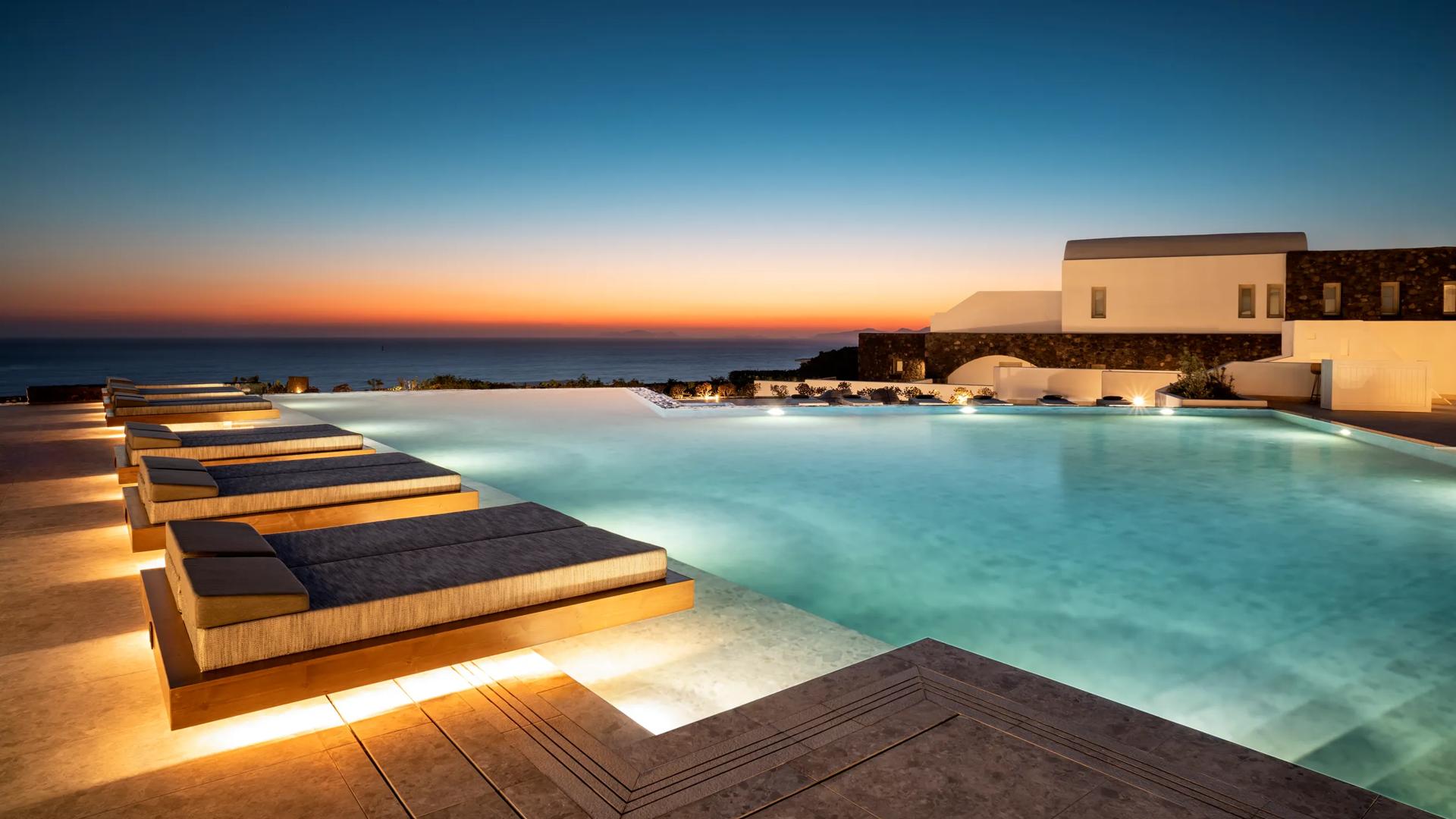 The outdoor infinity Pool at Santo Pure Oia Suites & Villas in Santorini, Greece, which features sun loungers overlooking the Aegean Sea.