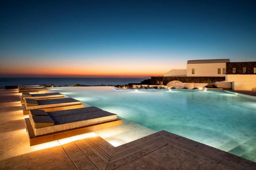 The outdoor infinity Pool at Santo Pure Oia Suites & Villas in Santorini, Greece, which features sun loungers overlooking the Aegean Sea.