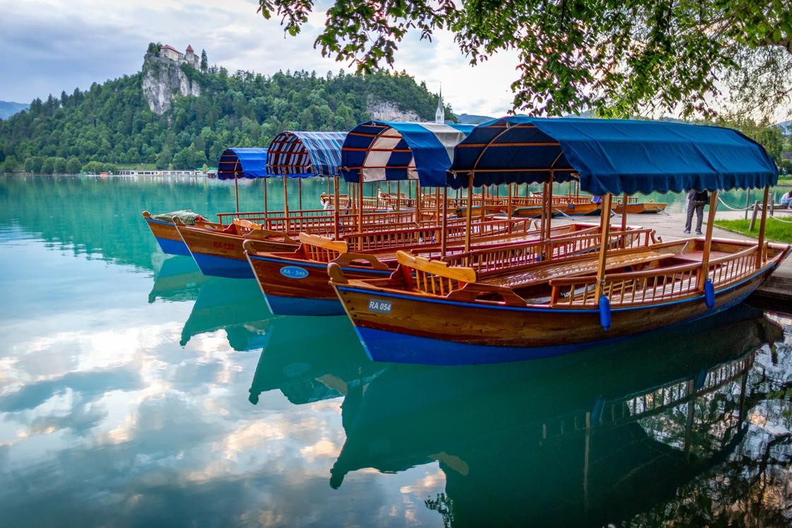 Wooden boats with blue awnings at the dock in Lake Bled.