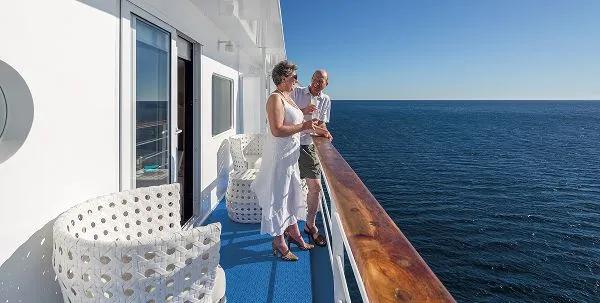 A couple enjoying the view from the private balcony of the Galapagos Legend ship while cruising the Galapagos Islands.