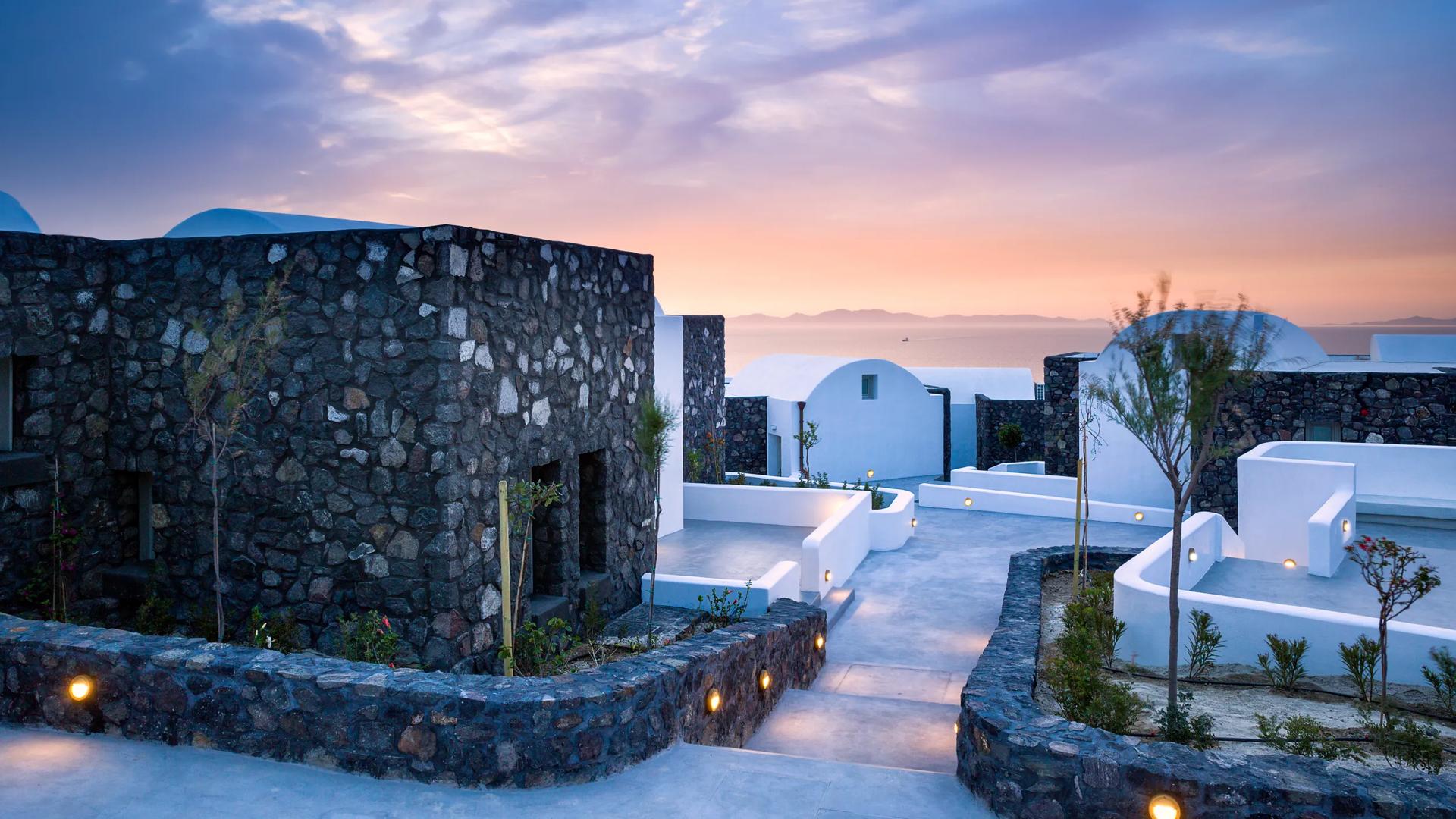 The Santo Pure Oia Suites & Villas in Oia, Santorini, known for its Cycladic architecture with minimalist buildings constructed from dark volcanic stone masonry alongside traditional whitewashed, domed structures, and scenic sea views.