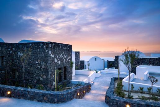 The Santo Pure Oia Suites & Villas in Oia, Santorini, known for its Cycladic architecture with minimalist buildings constructed from dark volcanic stone masonry alongside traditional whitewashed, domed structures, and scenic sea views.