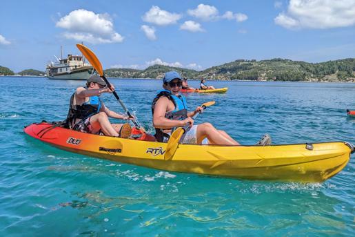 Two guests kayaking in a yellow and red tandem sit-on-top kayak, enjoying Croatia’s Dalmatian Islands.