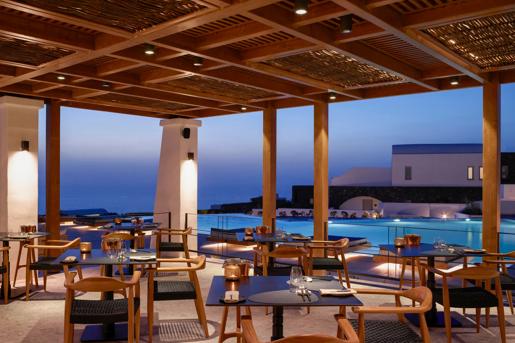 The Alios Ilios restaurant in Santorini, Greece, features a covered outdoor dining terrace overlooking an infinity pool and the Aegean Sea.