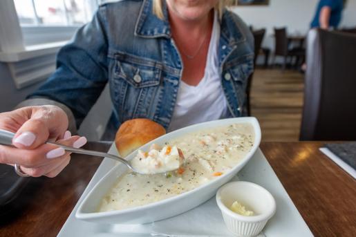 Young woman savoring a spoonful of delicious seafood chowder in Nova Scotia.