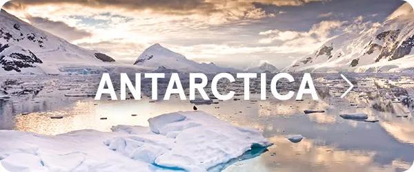 Panoramic view of icy waters filled with floating icebergs surrounded by snow-covered mountains under a warm sky, with the word "ANTARCTICA" displayed in large white text across the center.