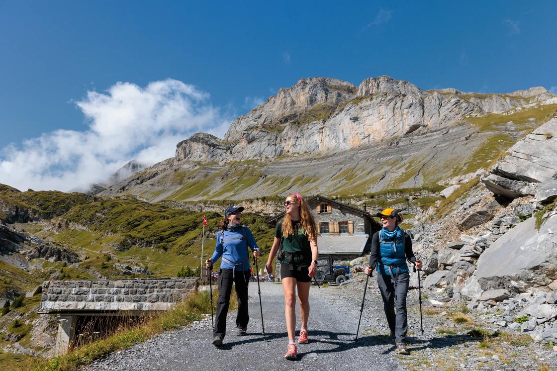 Three hikers in the Swiss Alps, leaving a refugio with the mountains behind them.