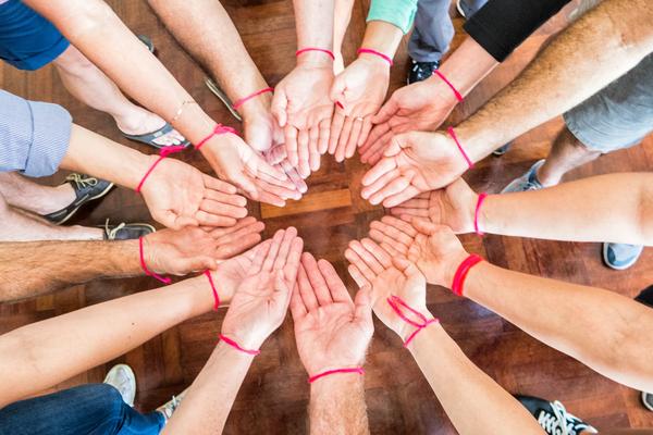 A large group of people stacking their hands together in a circle.