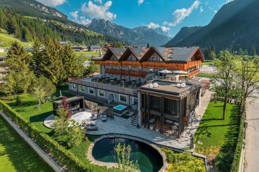An exterior view of the Alp Hotel, set against a scenic mountainous backdrop.