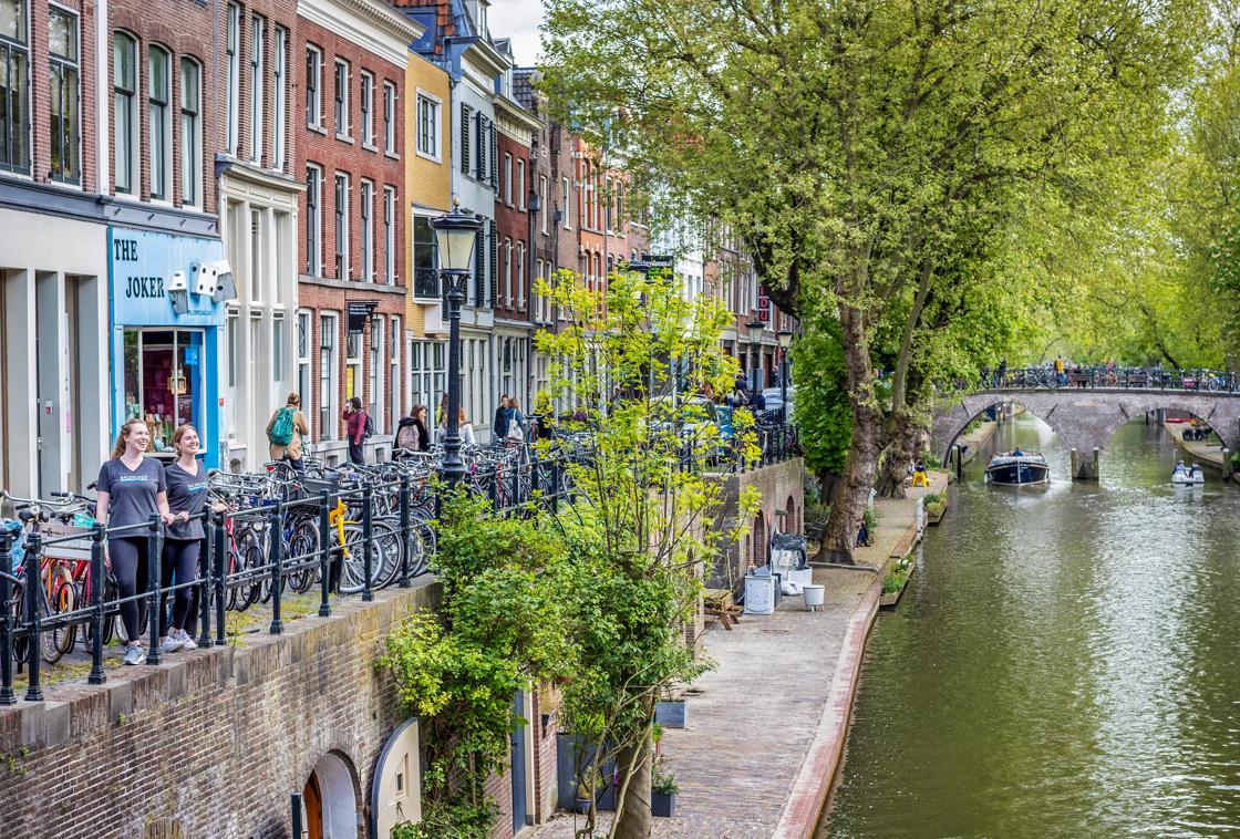 Two women in Backroads t-shirts look out over a canal in the Netherlands, surrounded by bicycles.