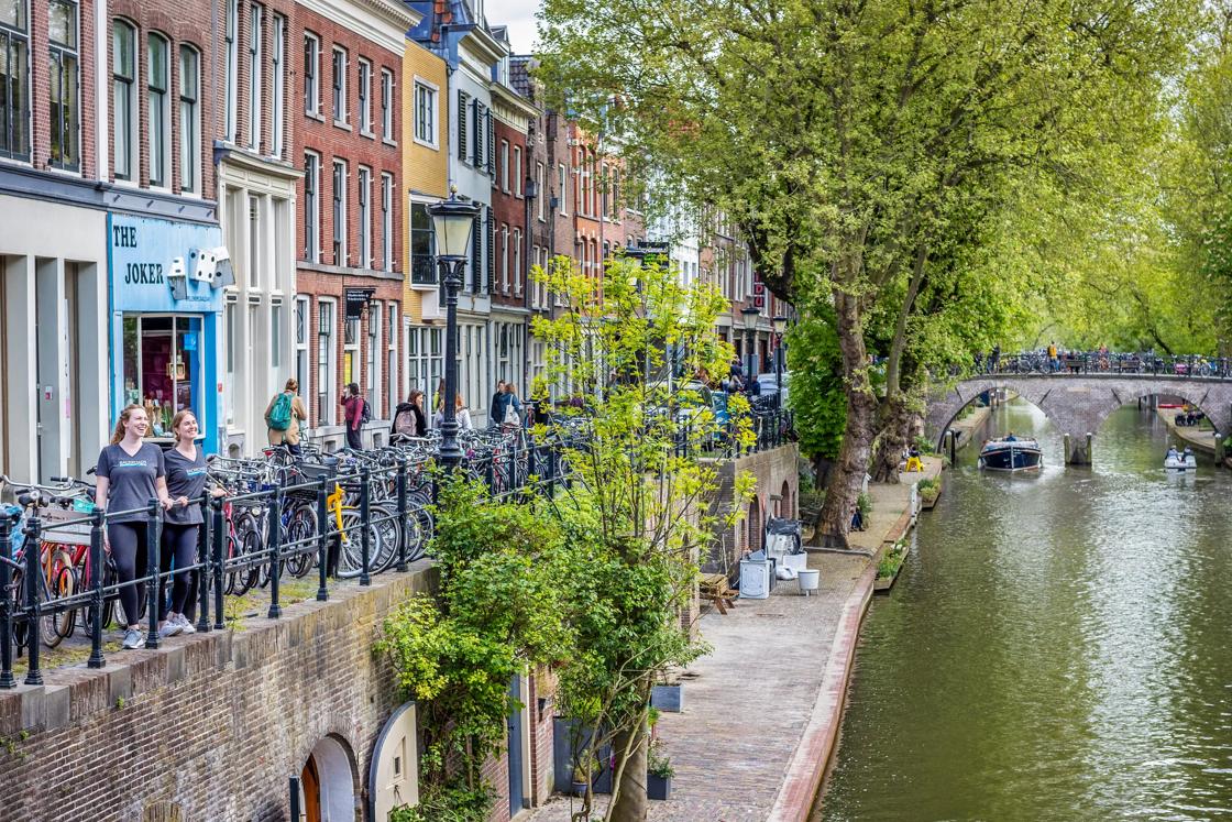 Two women in Backroads t-shirts look out over a canal in the Netherlands, surrounded by bicycles.