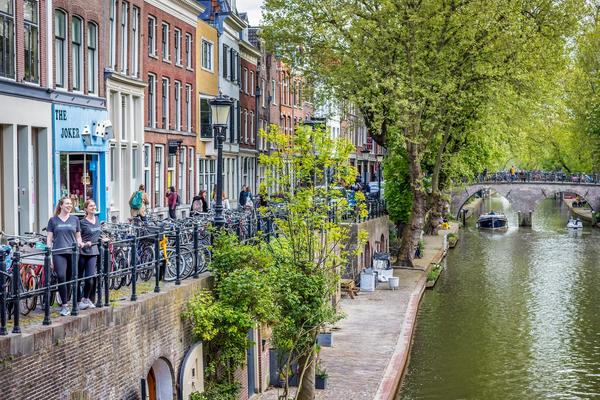 Two women in Backroads t-shirts look out over a canal in the Netherlands, surrounded by bicycles.