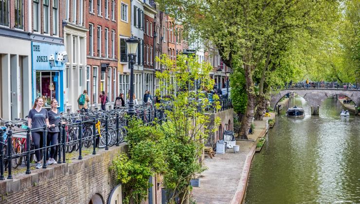 Two women in Backroads t-shirts look out over a canal in the Netherlands, surrounded by bicycles.