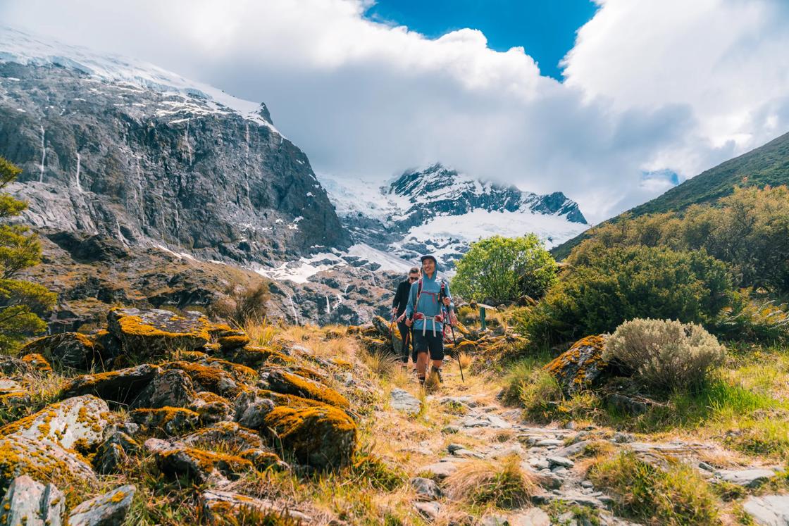 Hiking on New Zealand's South Island with snowcapped mountains in the background.