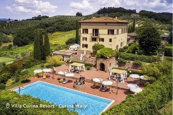 The Villa Curina Resort and outdoor pool, surrounded by rolling hills, vineyards, and olive groves is located in the Chianti hills of Castelnuovo Berardenga, Tuscany, Italy. Text overlay reads: Villa Curina Resort, Curina Italy.