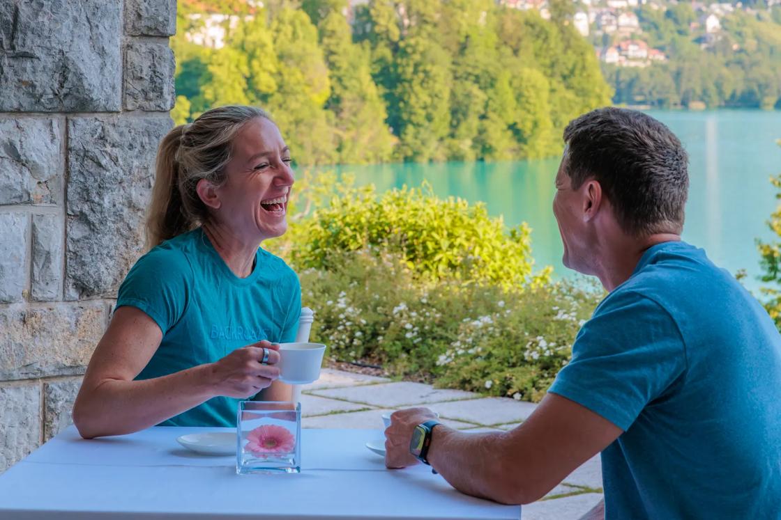 A couple enjoying a laugh together at a cafe on a lake in Slovenia.