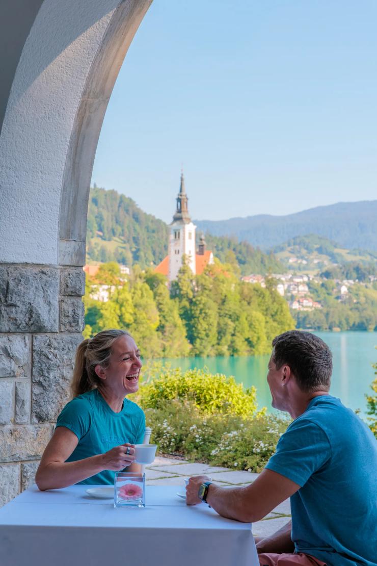 A couple enjoying a laugh together at a cafe on a lake in Slovenia.
