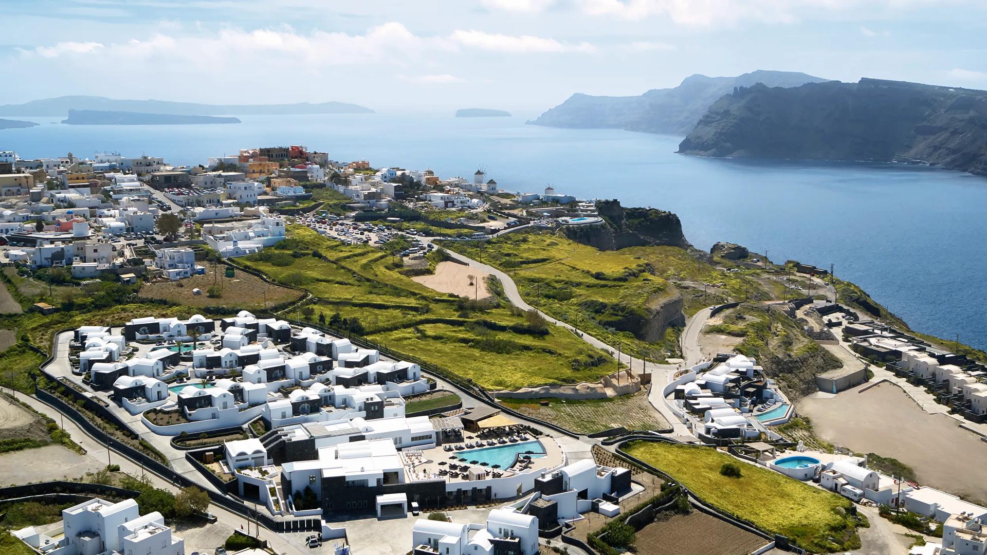 Aerial view of the Santo Pure Oia Suites and Villas in Santorini, characterized by its whitewashed architecture and multiple swimming pools.
