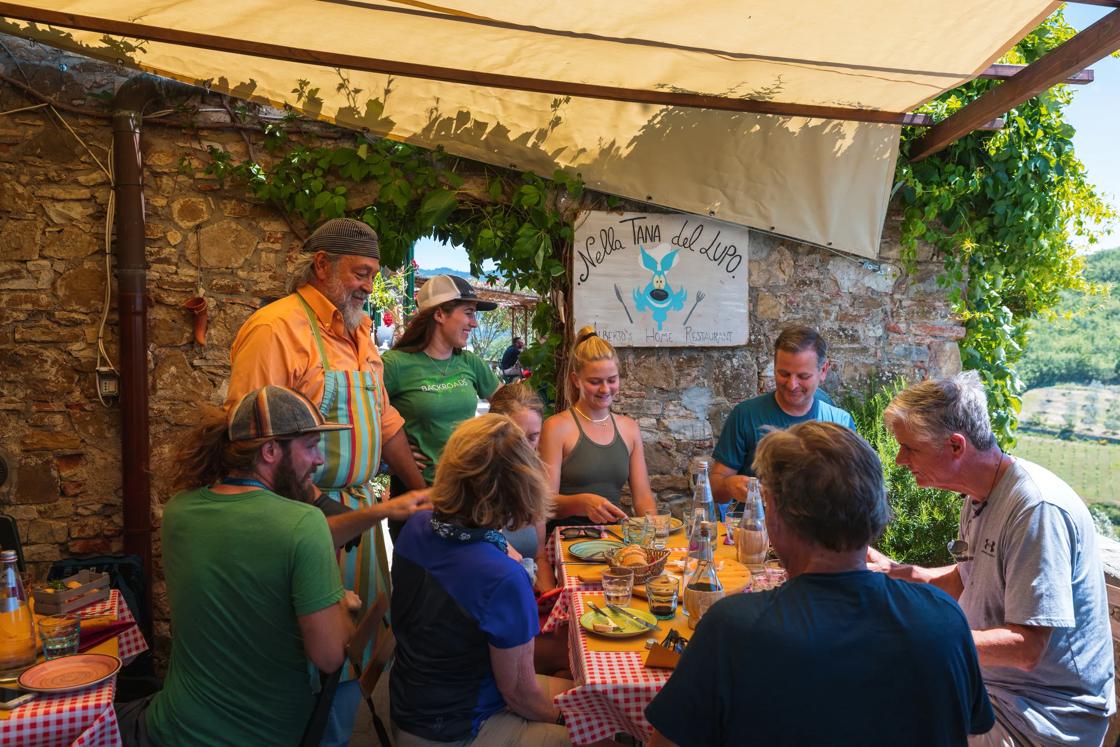 A gathering of friends around a table on an outdoor patio in Tuscany.
