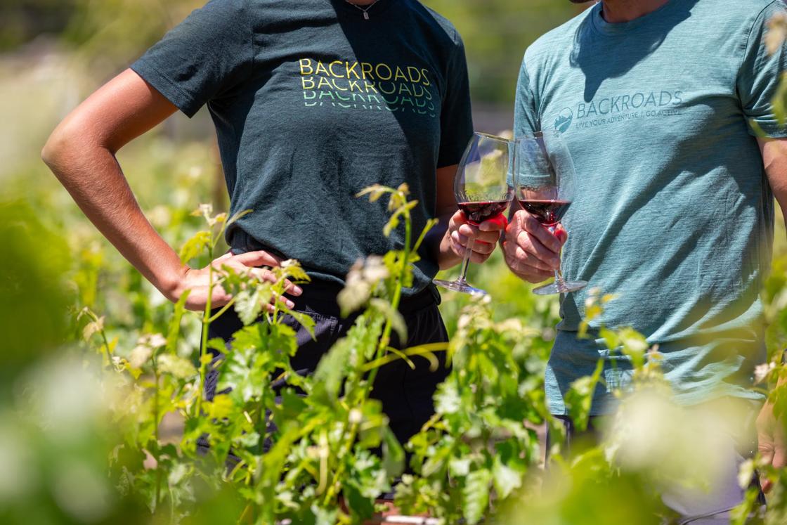 Two guests wearing Backroads t-shirts enjoying a glass of red wine.